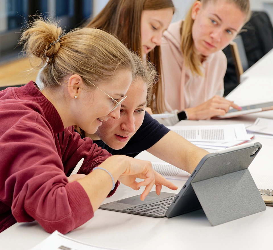 Studentinnen arbeiten gemeinsam an einem Tablet in einem Seminar an der KSH Muenchen.