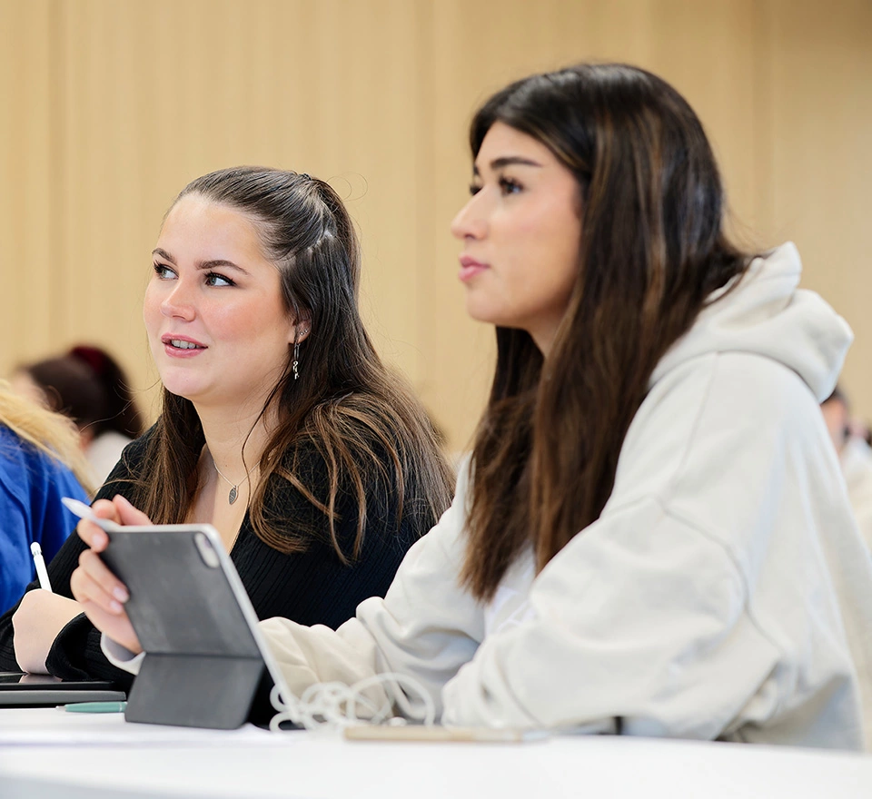 Zwei interessierte Studentinnen mit einem Tablet in einem Seminar.